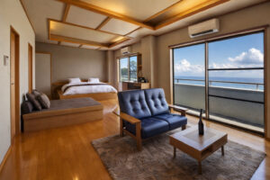 Chambre avec lit, canapé et balcon face à l’océan