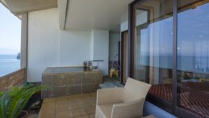 Bain privatif sur le balcon à côté des fenêtres d’une chambre face à l’océan