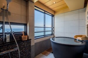 Bain privé près d’une grande fenêtre avec vue sur l’océan