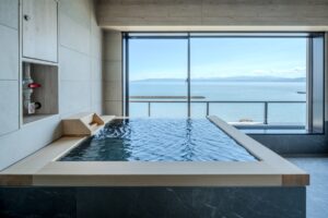 Bain privé avec vue sur l’océan depuis une grande fenêtre