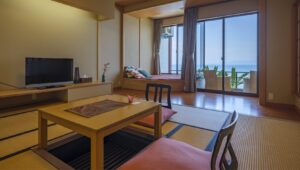 Chambre en tatami avec table basse, chaises de sol et banquette près de la fenêtre