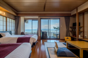 Lits jumeaux et coin tatami face à un balcon avec vue sur l’océan