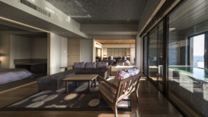 Habitación con zona de estar junto a las ventanas y bañera con vista al mar