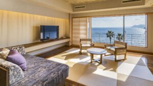 Zona de estar de habitación con tatami frente a una ventana con vista al océano