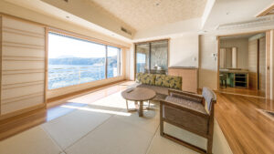 Habitación de tatami con sillas, mesa y ventana con vista al océano