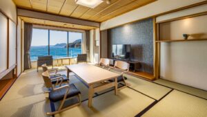 Habitación de tatami con mesa baja, sillas y vistas al océano