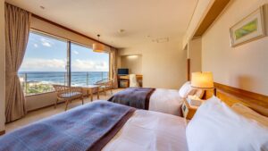 Camas individuales en una habitación con ventana con vista al mar