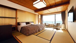 Camas individuales en habitación de tatami con balcón y vista al mar