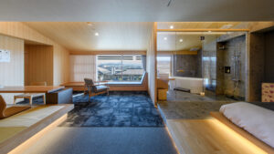 Guest room with seating area, bed, and glass-walled bath