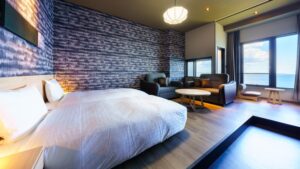 Camera da letto con due letti, divano e finestra con vista sull’oceano