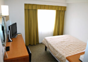 Letto singolo accanto alla scrivania e alla finestra