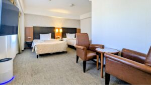 Due letti con poltrone e tavolo nella camera