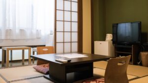 Habitación de tatami con mesa baja, sillas de suelo y TV
