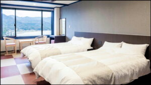 Zwei Einzelbetten neben einem Fenster mit Bergblick