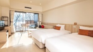 バルコニー付きの明るい客室にあるベッド2台