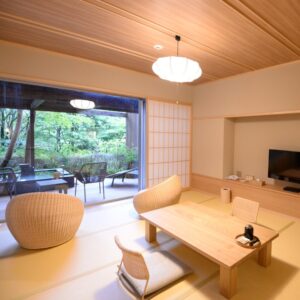 Chambre en tatami avec table basse et chaises, vue sur le jardin