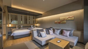 Coin salon avec canapé dans la chambre, avec deux lits à l’arrière