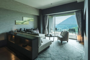 Chambre avec lit, chaises et vue sur la montagne depuis le balcon