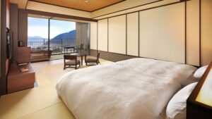Ropa de cama futón en una habitación de tatami con vistas a la montaña