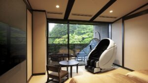 Zona de estar de la habitación con sillón de masaje junto al balcón