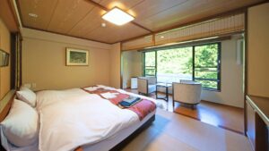 Chambre avec grand lit, chaises et vue par la fenêtre