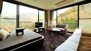 Chambre avec lits, canapé et fenêtres donnant sur la montagne