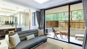 Sofa seating area beside terrace and glass-walled bath
