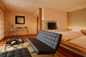 Chambre avec lits plateforme et coin salon avec canapé noir