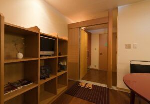 Entrée de la chambre avec étagères, chaussons et table
