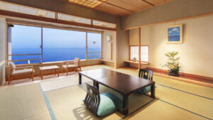 Chambre en tatami avec table basse, chaises et vue sur l’océan