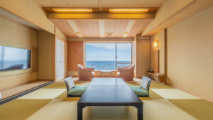 Chambre en tatami avec table basse, chaises et vue sur l’océan