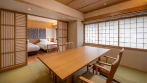 Chambre en tatami avec table en bois, chaises et lits