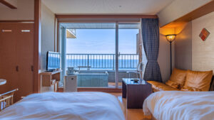 Lits jumeaux dans une chambre donnant sur un balcon et une vue sur l’océan