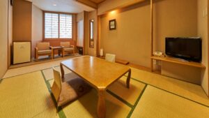 Habitación de tatami con mesa baja, sillas y televisión