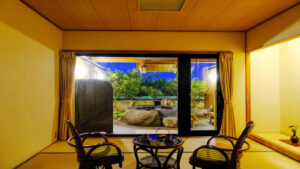 Vue sur le jardin à travers la fenêtre de la chambre avec chaises et table
