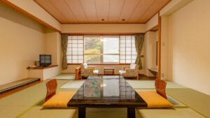 窓際に低いテーブルと椅子がある畳の部屋