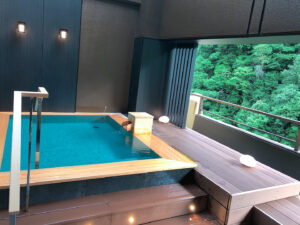 Private bath beside an open balcony with forest view