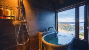 Baignoire privée près de la fenêtre avec vue sur l’eau