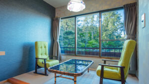 窓辺に置かれたアームチェア2脚とガラステーブル