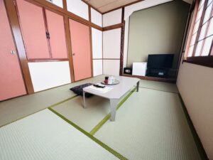 Chambre en tatami avec table basse, coussins de sol et télévision