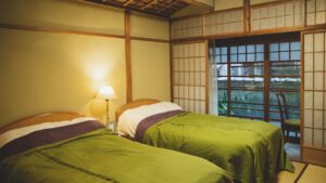 Camas individuales en una habitación de tatami junto a ventanas shoji