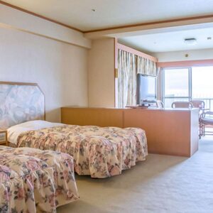 Lits jumeaux dans une chambre avec banquette près de la fenêtre