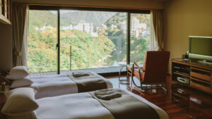 Twin beds facing a large window with mountain view