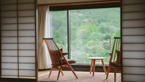 Two wooden chairs and table by window