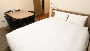 Letto matrimoniale accanto a una piccola scrivania e una sedia