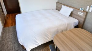 Letto matrimoniale accanto a un piccolo tavolo in legno