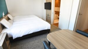 Letto matrimoniale in camera con tavolo e porta del bagno