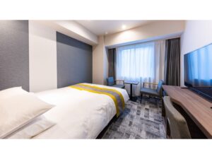 Guest room with bed, desk, chairs, and television