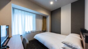 Single bed beside window and desk in guest room