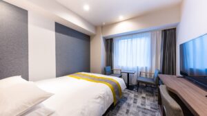 Twin beds beside desk and window seating area